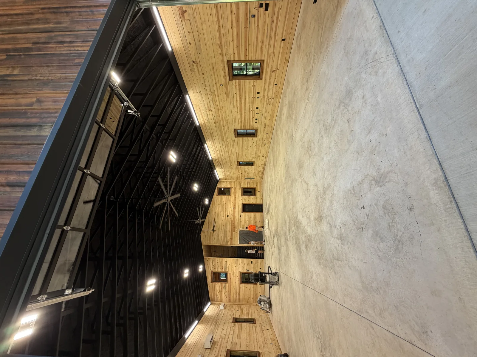 Tan flake floor filling a pine-clad barndominium under a black ceiling