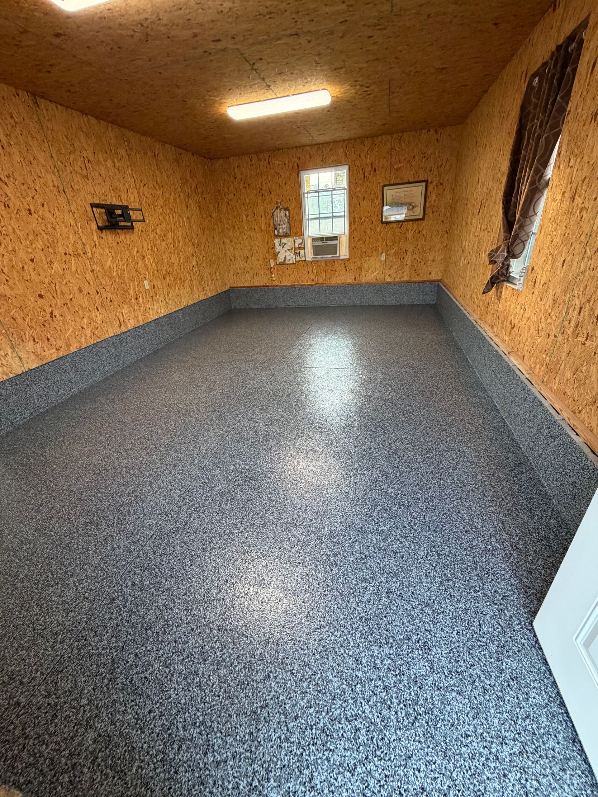 Gray and white flake floor with a coved base running wall to wall in a finished outbuilding