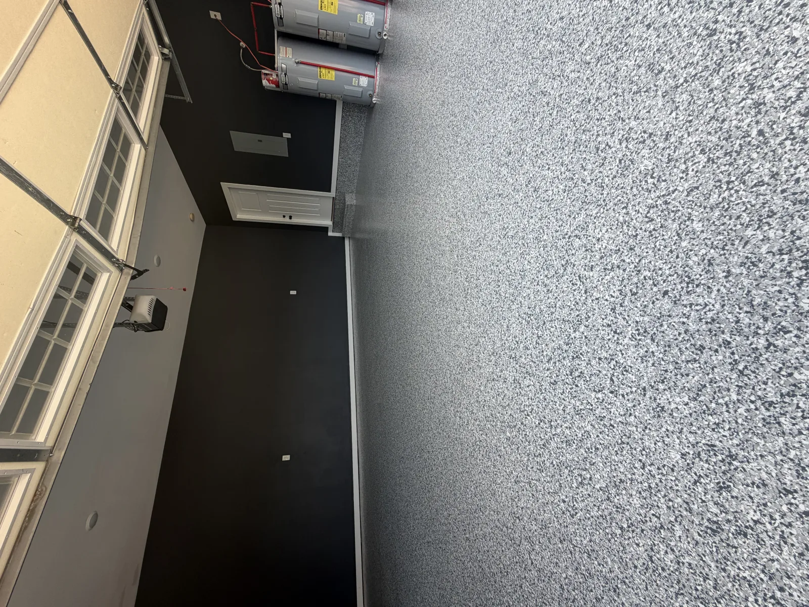 Dark charcoal flake floor around an open floor hatch in a wide garage