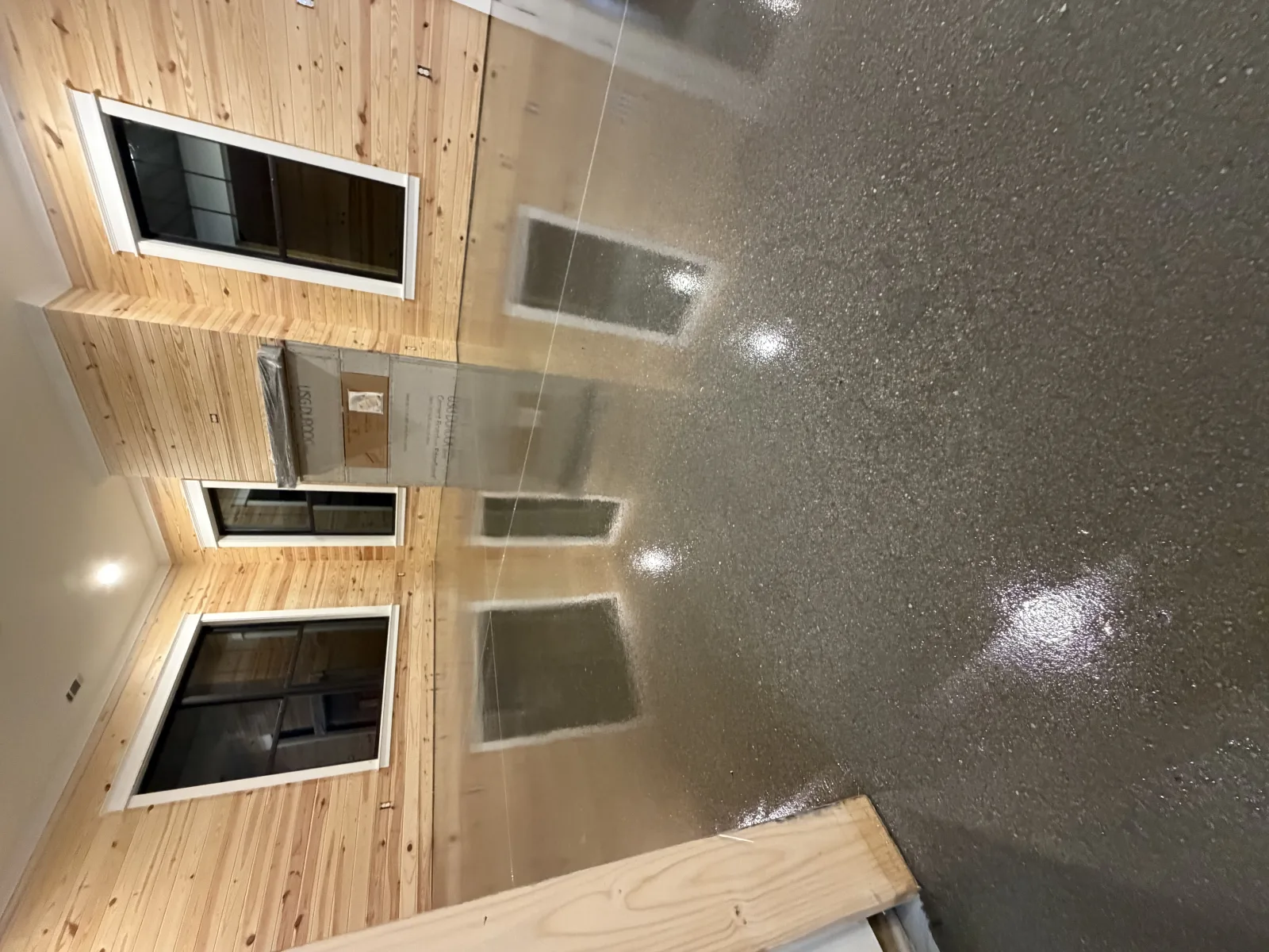 Grey and white flake floor in a garage with charcoal walls and water heaters along the back