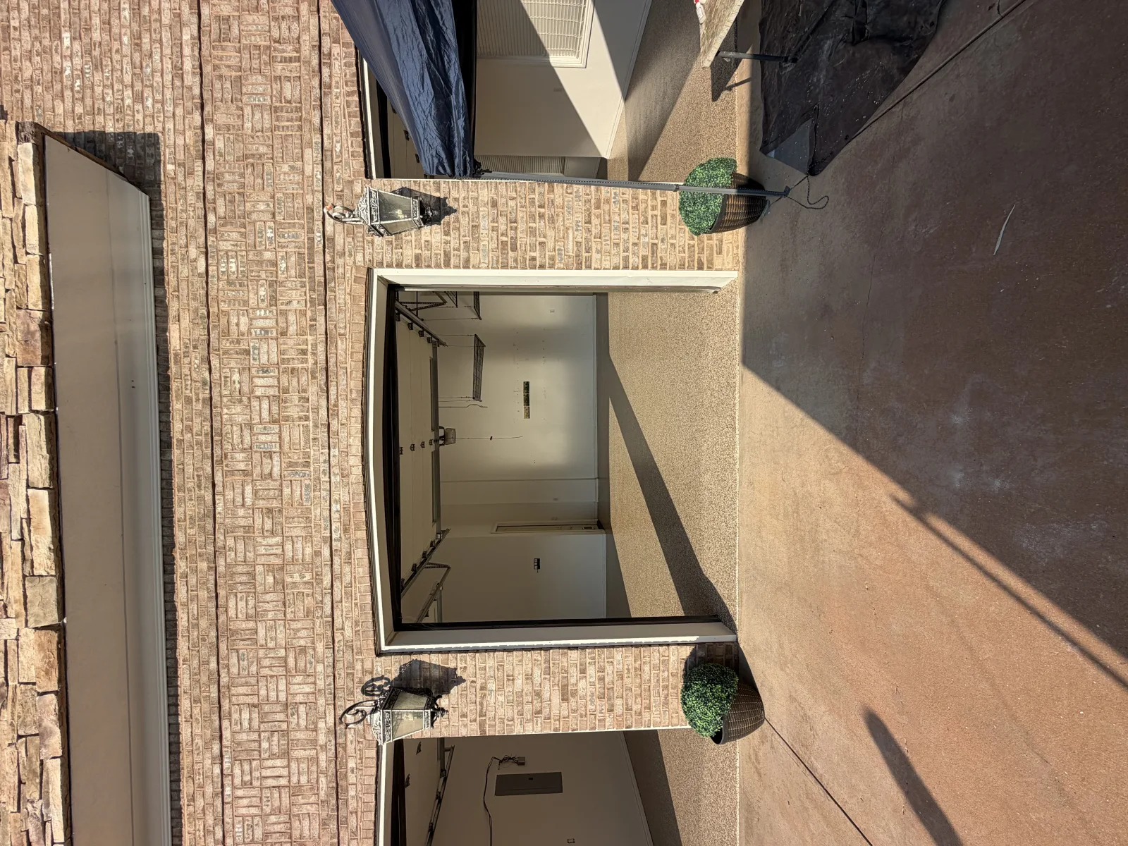 Tan and cream flake floor lit by sun through an open garage door, storage racks on the wall