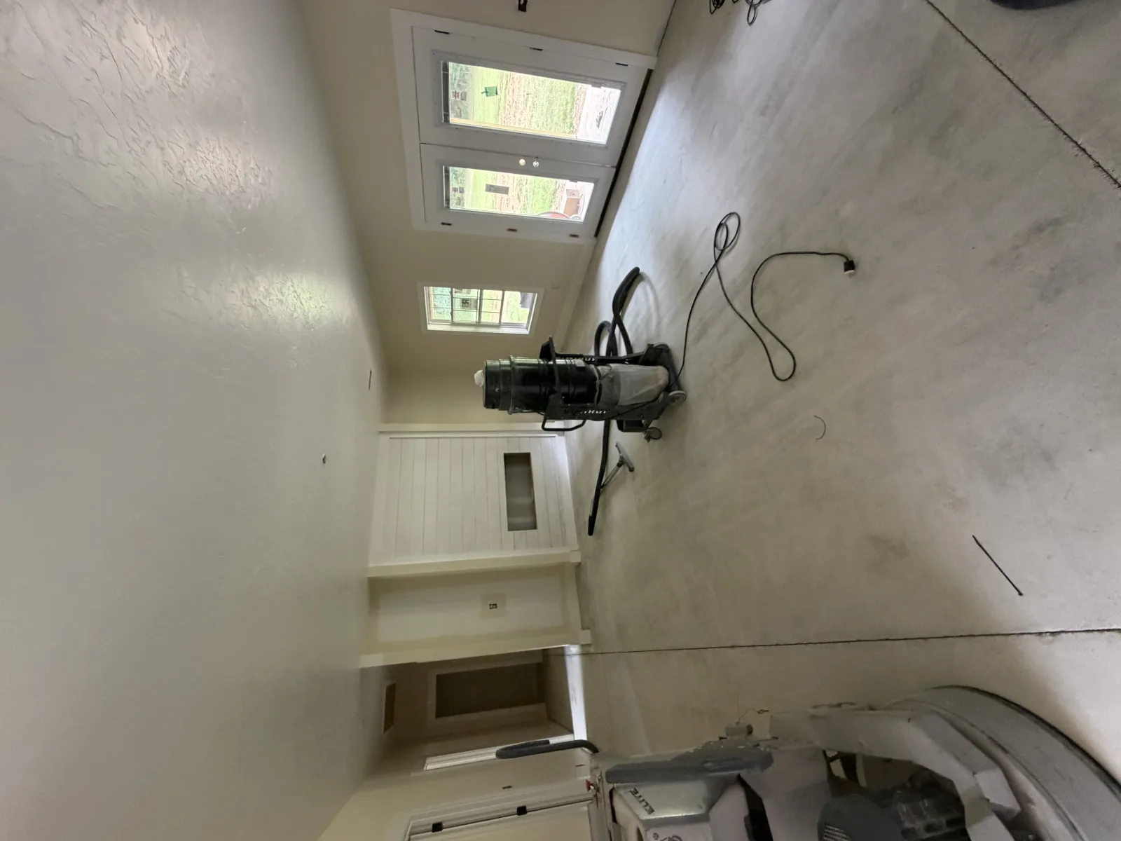 Deep brown stained and sealed floor running through an empty house toward patio doors