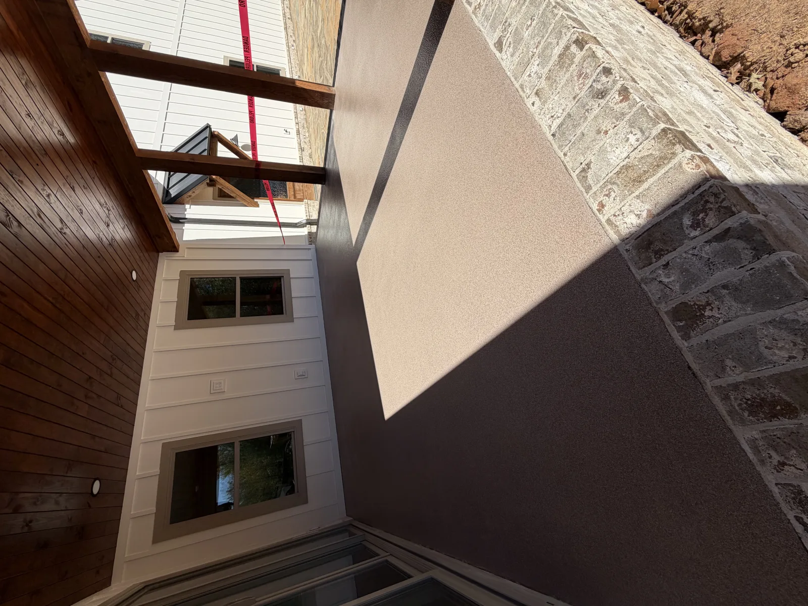 Grey flake pool deck wrapping a rectangular in-ground pool beside a brick house
