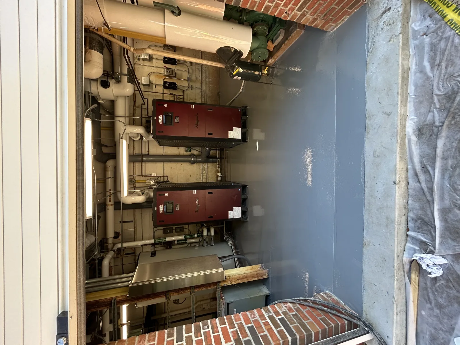 Coated pump room floor seen from above, coved up to the plinth around blue valves