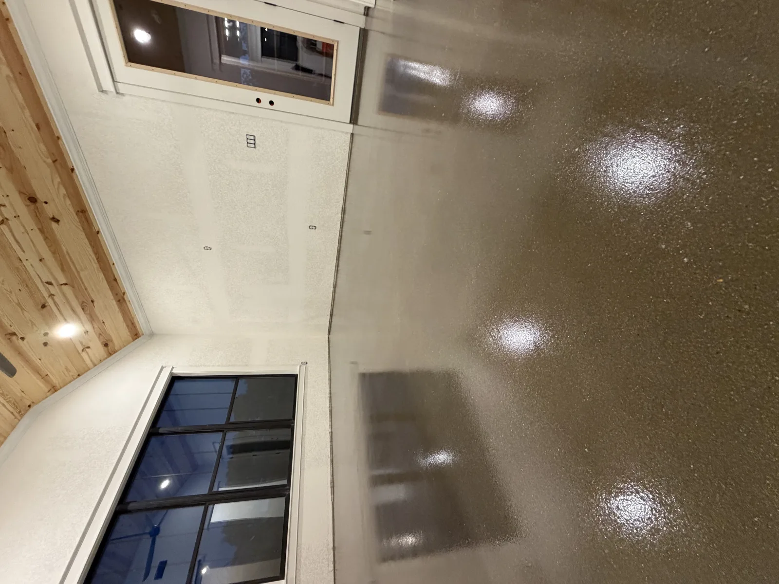 Stained and sealed floor mirroring the windows of a pine-lined room