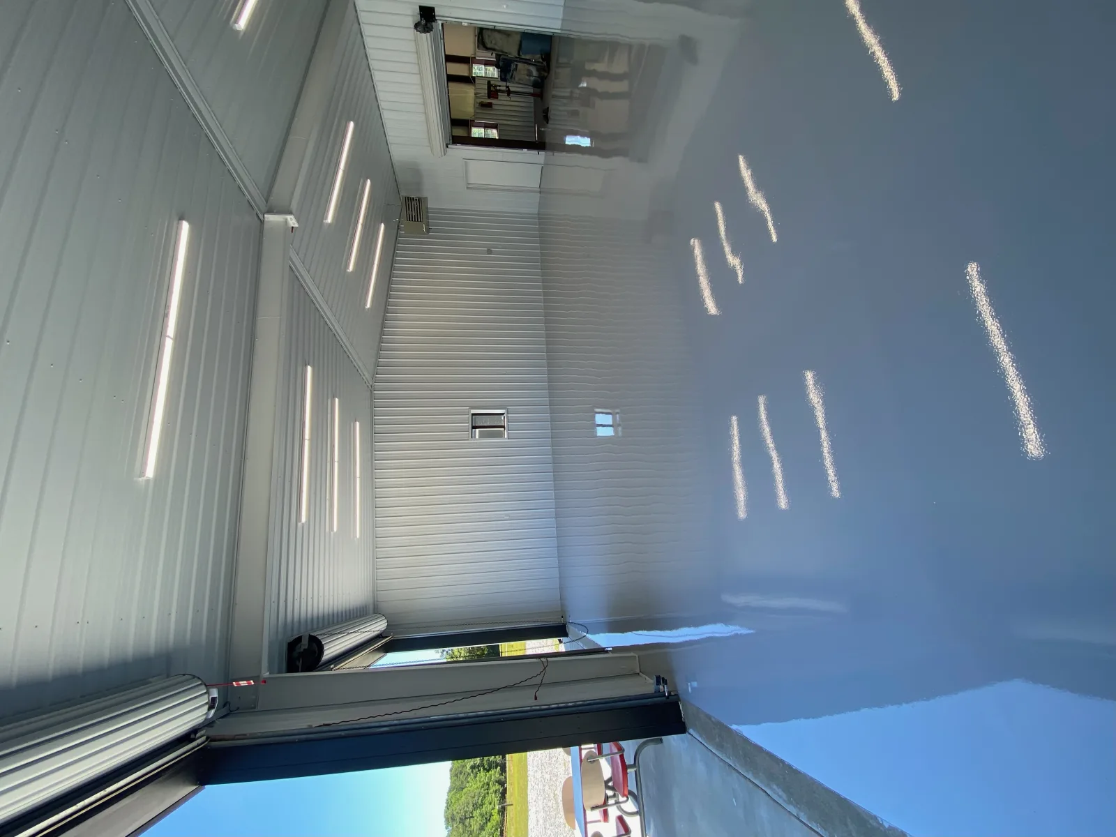 Grey solid colour floor running to an open roller door with daylight beyond