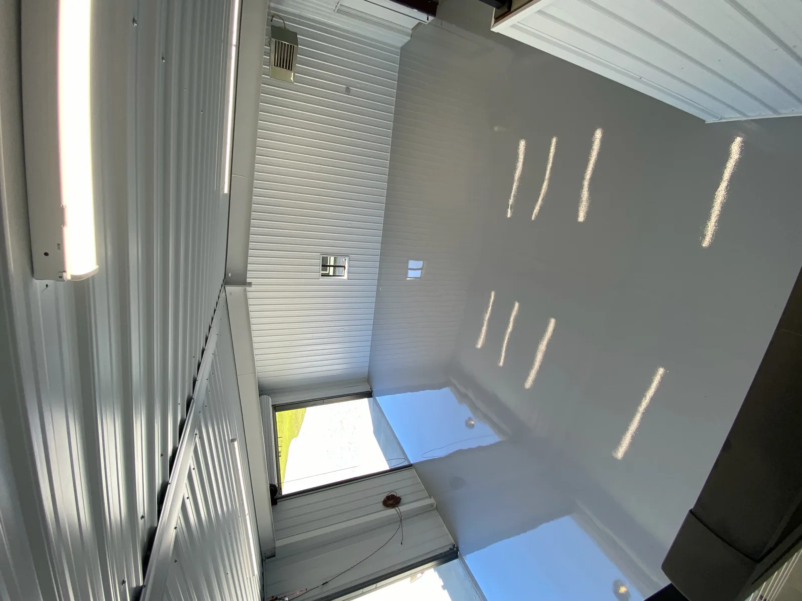 High-gloss grey floor mirroring the ceiling lights of a white metal shop