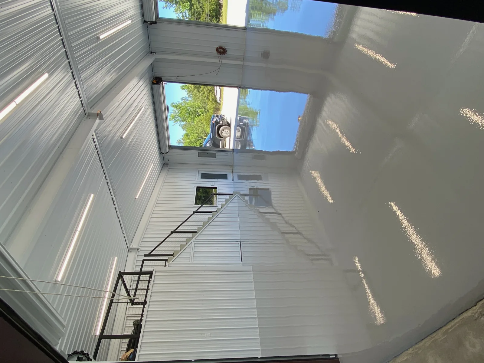 Glossy grey shop floor beneath a steel mezzanine staircase