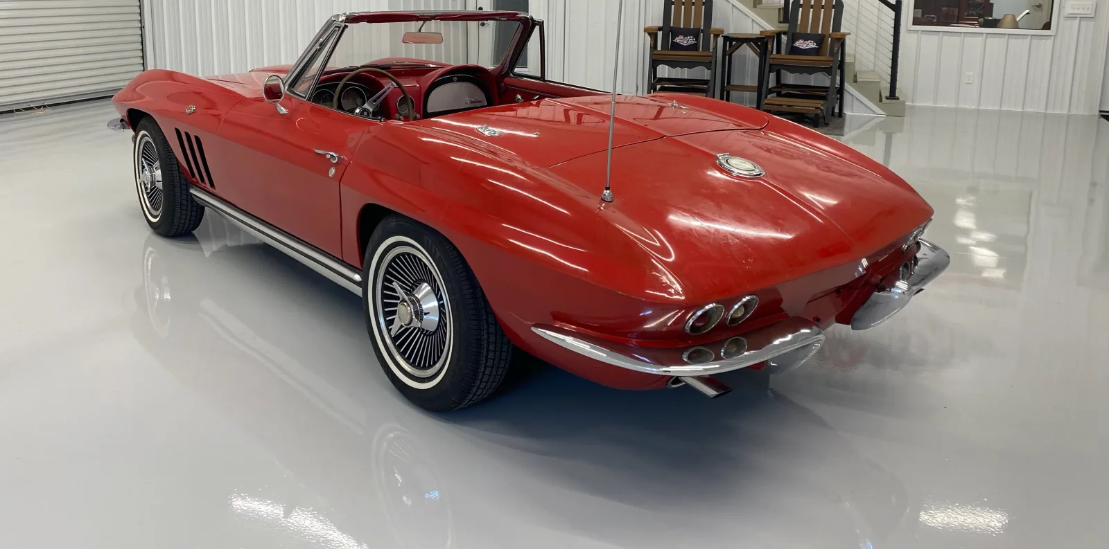 High-gloss white showroom floor holding the reflection of a red classic car