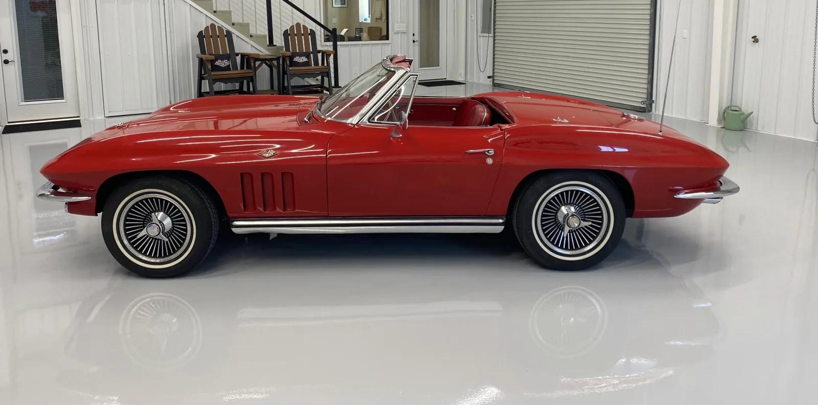 Mirror-finish showroom floor reflecting a red classic convertible full length